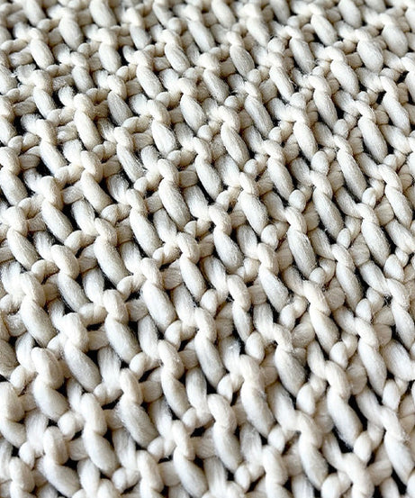 Weiche, grob gestrickte cremefarbene Überwurfdecke